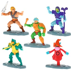 May include: A set of six Masters of the Universe action figures. The figures are made of plastic and are painted in bright colors. The figures include He-Man, Skeletor, Man-At-Arms, Beast Man, Teela, and Evil-Lyn. Each figure stands on a small plastic base.