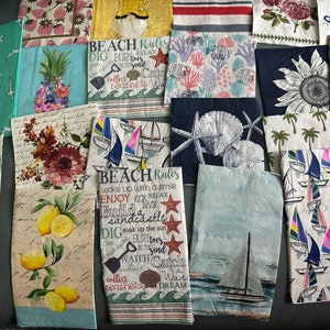 May include: A collection of colorful paper napkins with beach-themed designs and text. The napkins feature images of seashells, starfish, sailboats, and lemons. The text on the napkins includes phrases like "Beach Rules", "Enjoy", "Build a Sandcastle", and "Collect Seashells".