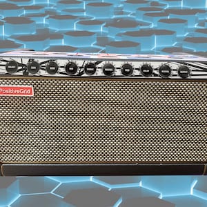 May include: A black guitar amplifier with a brown speaker grille and a white and black graphic design. The amplifier has multiple knobs labelled "Select", "Gain", "Bass", "Mid", "Treble", "Master", "Mod", "Delay", "Reverb", and "Output". The amplifier has a red label that says "PositiveGrid".