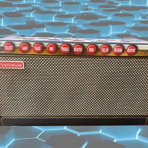 May include: A black and gold PositiveGrid guitar amplifier with a speaker grill and multiple knobs labeled "Select", "Gain", "Bass", "Mid", "Treble", "Master", "Mod", "Delay", "Reverb", and "Output".