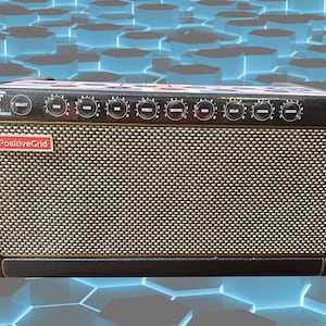 May include: A black guitar amplifier with gold trim and a speaker grille. The amplifier has a variety of knobs and buttons, including a "Positive Grid" logo.