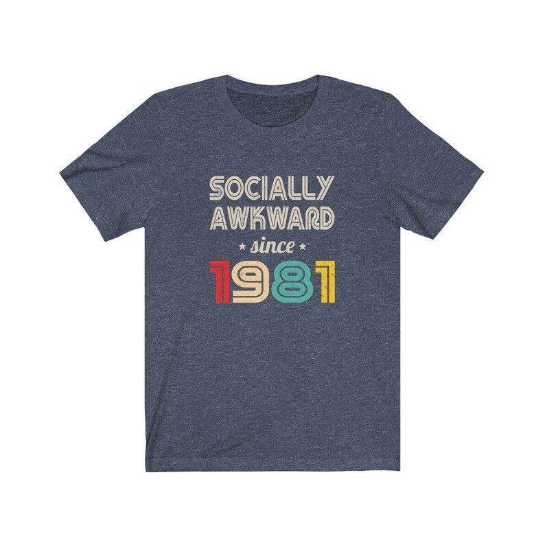 May include: A navy blue t-shirt with the text "Socially Awkward since 1981" in a retro style font. The numbers are in different colors: red, yellow, green, and blue.