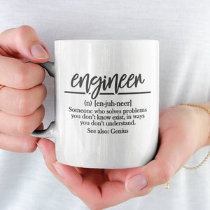 Op de afbeelding: Een witte keramische mok met een zwart ontwerp met de tekst "engineen (n) [en-juh-neer] Someone who solves problems you don't know exist, in ways you don't understand. See also: Genius"