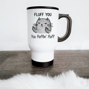Könnte beinhalten: Weiße Reise-Thermoskanne mit schwarzem Griff und Deckel. Die Tasse zeigt eine Comic-Katze mit dem Text "Fluff You" und "You Fluffin' Fluff" darauf.