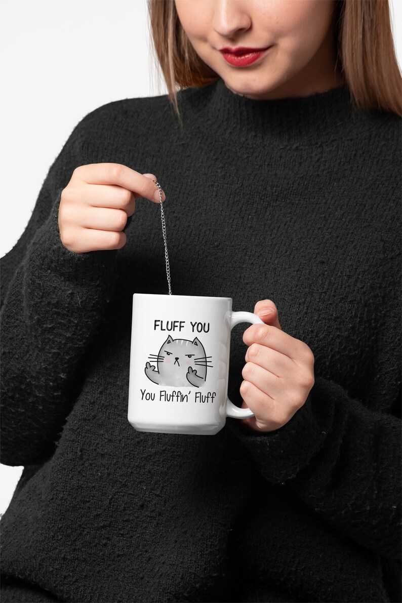 May include: White ceramic mug with a black and gray cartoon cat with the text "Fluff You You Fluffin' Fluff" printed on it.