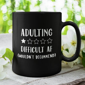 May include: Black coffee mug with white text that reads "Adulting Difficult AF (Wouldn't Recommend)" and a rating of one out of five stars.