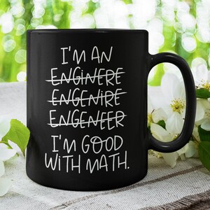 May include: Black coffee mug with white text that reads "I'm an engineer I'm good with math." The word "engineer" is crossed out multiple times.
