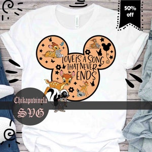 May include: A white t-shirt with a peach-colored Mickey Mouse head design. The design features Bambi and Thumper from the Disney movie Bambi, along with the text "Love is a song that never ends".