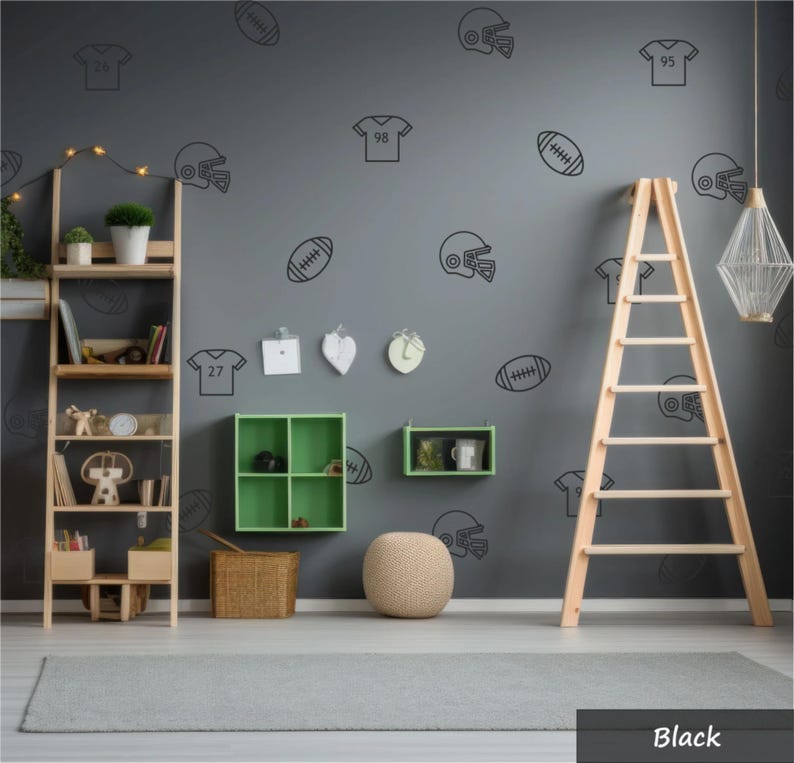 May include: A dark grey wall featuring black line art decals of football helmets, jerseys with numbers, and footballs. The wall includes a wooden shelving unit, a green four-compartment wall shelf, a small green shelf, and a wooden ladder.