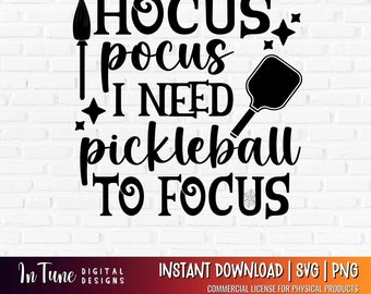 Op de afbeelding: Zwart-wit grafisch ontwerp met de tekst "Hocus Pocus I Need Pickleball To Focus". Bevat een heksenbezem, een pickleball-peddel, sterren en een spinnenweb. Het ontwerp staat op een witte bakstenen achtergrond.
