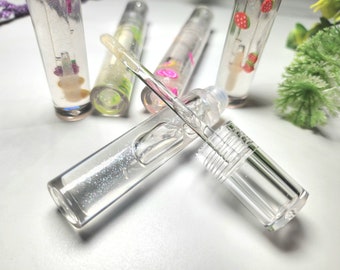 Può includere: Un set di tubetti di gloss per labbra trasparenti con glitter e disegni di diversi colori. I tubetti hanno un applicatore a bastoncino trasparente con una punta argentata.