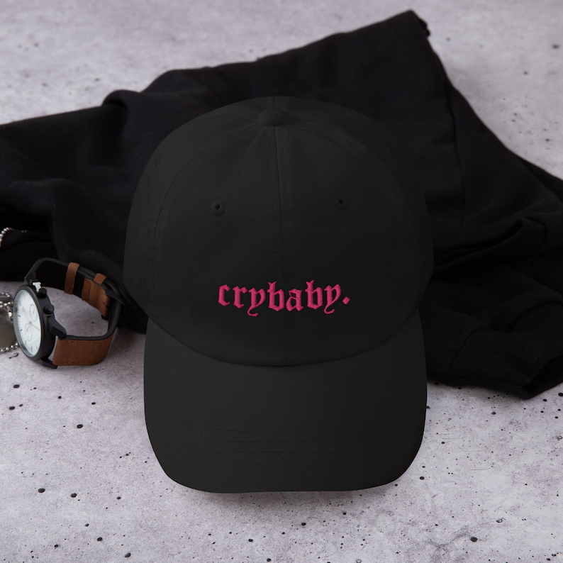Puede incluir: Gorra de b&eacute;isbol negra con un texto bordado en rosa que dice "crybaby."