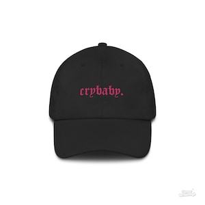 Puede incluir: Una gorra de b&eacute;isbol negra con texto bordado en rosa que dice "crybaby."
