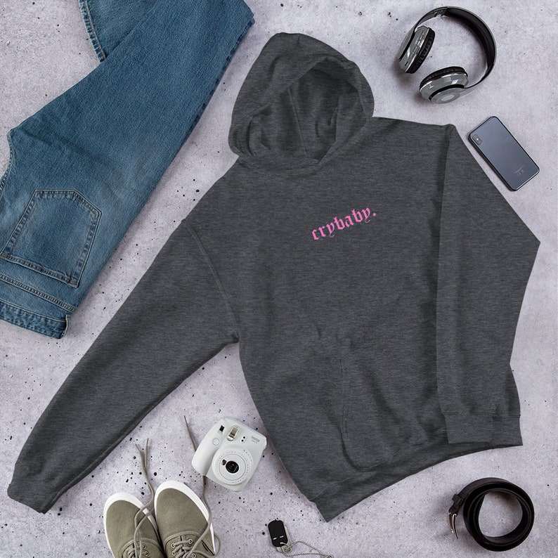 May include: A dark gray hooded sweatshirt with a pink embroidered design that says "crybaby."
