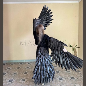 May include: Black feathered wings costume with a long tail. The wings are large and dramatic, with a realistic look. The tail is made of feathers and is attached to the back of the costume.