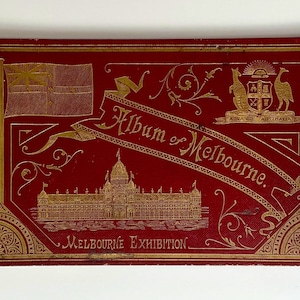 May include: A red album cover with gold lettering that reads "Album of Melbourne. Melbourne Exhibition." The cover features a gold illustration of a building, a flag, and a coat of arms.