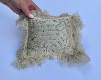 May include: A white satin pillow with a fringed border. The pillow is decorated with silver beads and a handwritten message that reads "Always till and you are mine, His for to have and to hold and protect this Lovely Babe 1864."