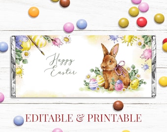 May include: Printable Easter chocolate bar wrapper featuring a cute brown bunny rabbit with pink ribbon, surrounded by colorful Easter eggs and flowers. The wrapper says "Happy Easter" in a green cursive font.