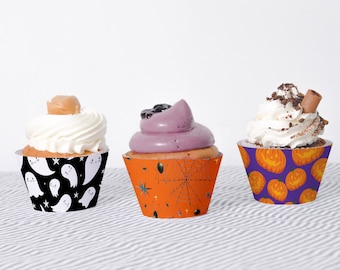 May include: Three Halloween-themed cupcake wrappers. One wrapper features a black background with white ghosts and stars. Another wrapper has an orange background with a black spiderweb and stars. The third wrapper has a purple background with orange jack-o'-lantern faces.