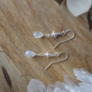 May include: A pair of silver earrings with teardrop-shaped moonstone stones and silver beads.