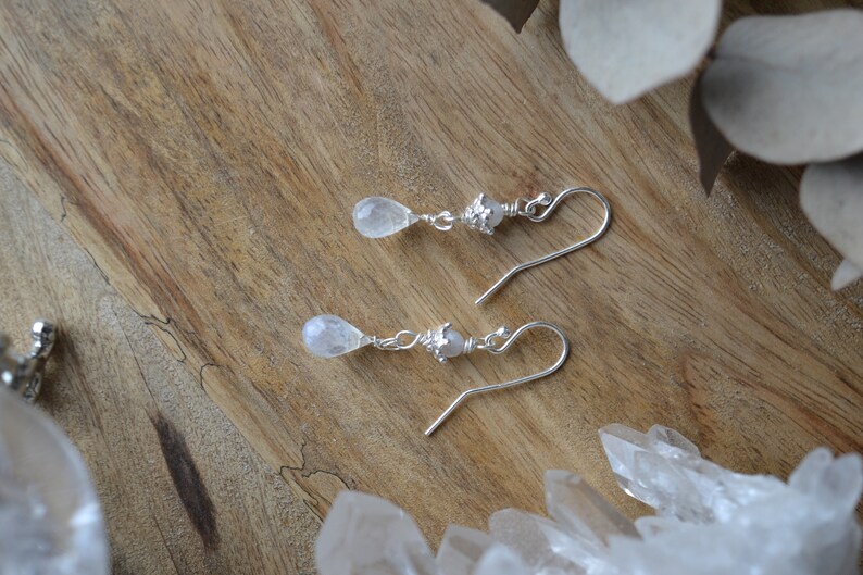 May include: A pair of silver earrings with teardrop-shaped moonstone stones and silver beads.