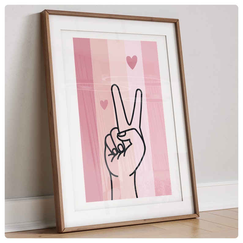K&ouml;nnte beinhalten: Ein gerahmter Druck mit einem rosa-wei&szlig; gestreiften Hintergrund. Eine schwarze Umrandung einer Hand, die das Friedenszeichen macht, befindet sich in der Mitte des Drucks. Auf dem Hintergrund befinden sich drei kleine rosa Herzen.