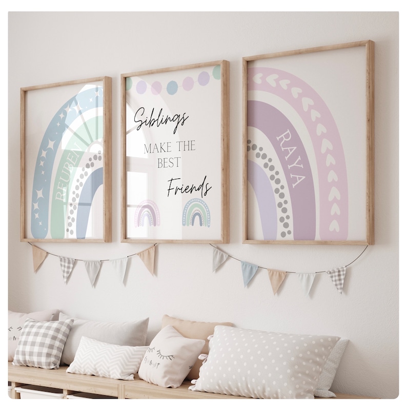 May include: Three framed prints with rainbow designs. The center print has the text "Siblings make the best friends" and two rainbow illustrations. The left print has a rainbow with stars and the text "Reuben". The right print has a rainbow with hearts and the text "Raya".