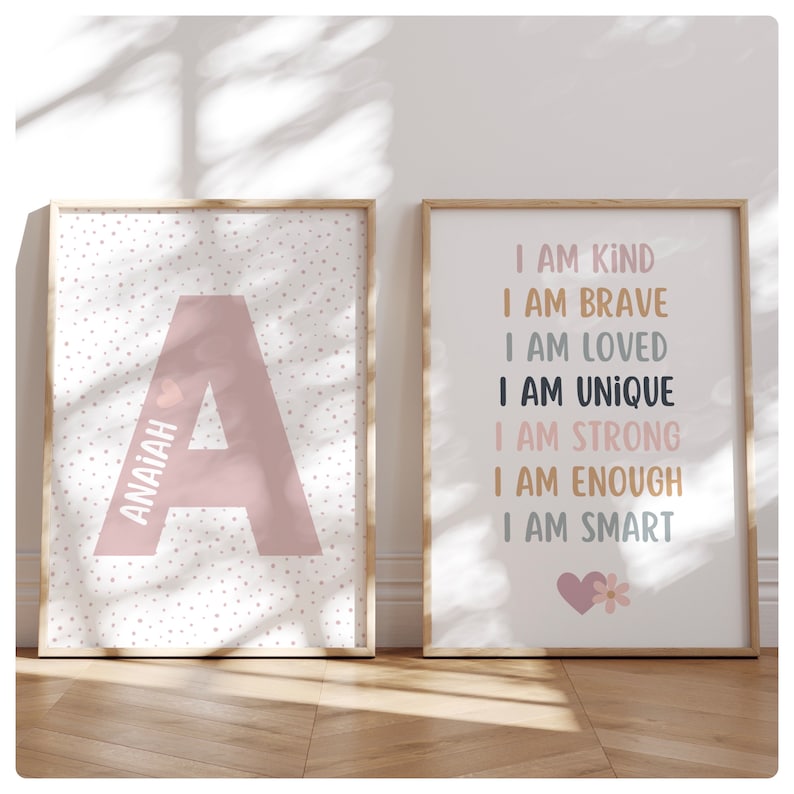 May include: Two framed prints with a pink and white polka dot background. The first print features a large pink letter A with the name Anaiah written vertically next to it. The second print has the text "I am kind, I am brave, I am loved, I am unique, I am strong, I am enough, I am smart" written in black and pink text. A small pink heart with a flower is at the bottom of the print.