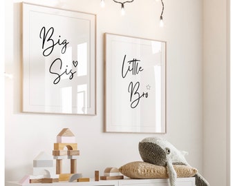 May include: Two framed prints with black calligraphy on a white background. The left print says "Big Sis" with a heart symbol. The right print says "Little Bro" with a star symbol. The prints are hanging on a white wall with a string of white lights above them.