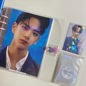 May include: A clear plastic binder with a photo of a man in a blue and white patterned shirt. The binder has a clear plastic pocket on the front with a holographic sticker that says "Diamond Shop".
