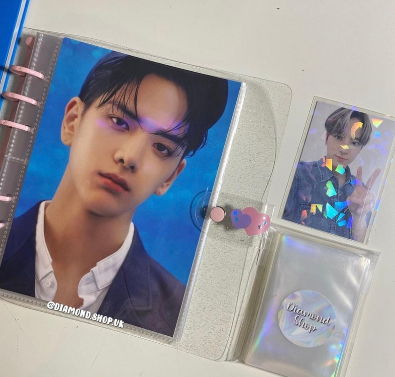 May include: A clear plastic binder with a photo of a man in a blue and white patterned shirt. The binder has a clear plastic pocket on the front with a holographic sticker that says "Diamond Shop".