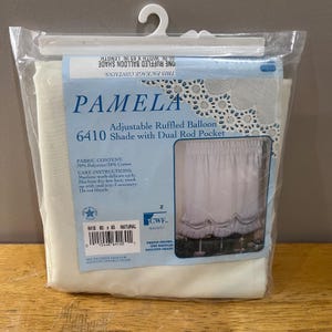 May include: A packaged Pamela adjustable ruffled balloon shade. The package includes a natural-colored shade with dimensions of 60 inches wide by 63 inches long. The fabric content is 70% polyester and 30% cotton.