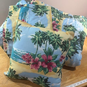 May include: A square throw pillow and a matching comforter featuring a tropical beach scene with green palm trees, pink hibiscus flowers, and a light blue sky. A white measuring tape is visible at the bottom, showing measurements in inches.
