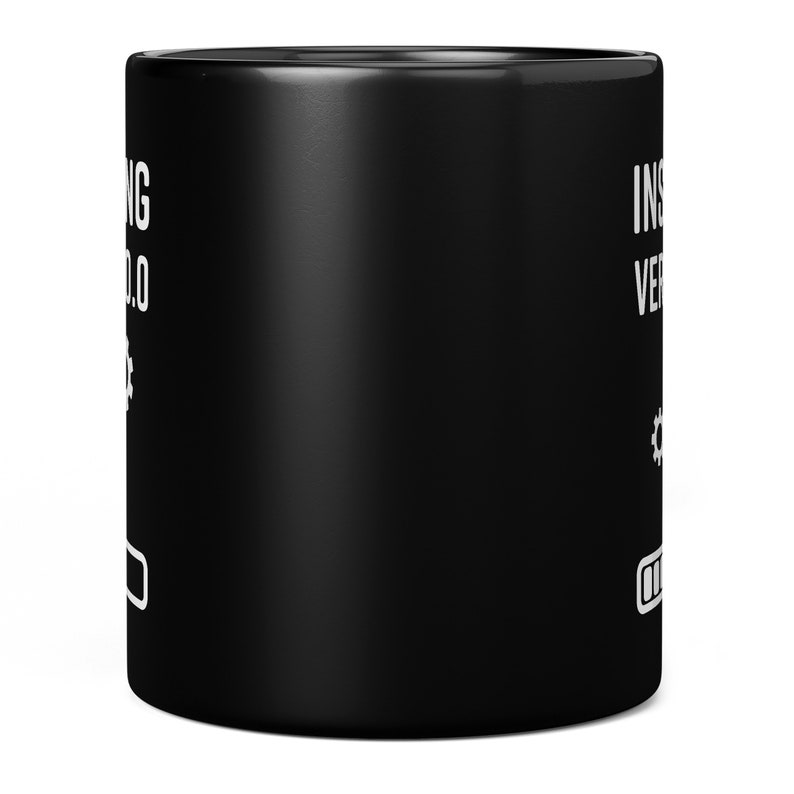 May include: Black ceramic coffee mug with white text that reads "Installing Version 1.0" with a gear icon and a progress bar.