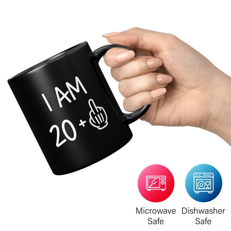 May include: Black ceramic coffee mug with white text that reads "I AM 20 +" with a middle finger emoji. The mug is microwave and dishwasher safe.