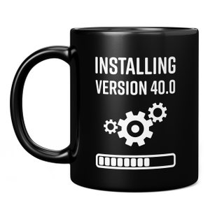 May include: Black coffee mug with white text that reads "Installing Version 40.0" with a progress bar and gears.