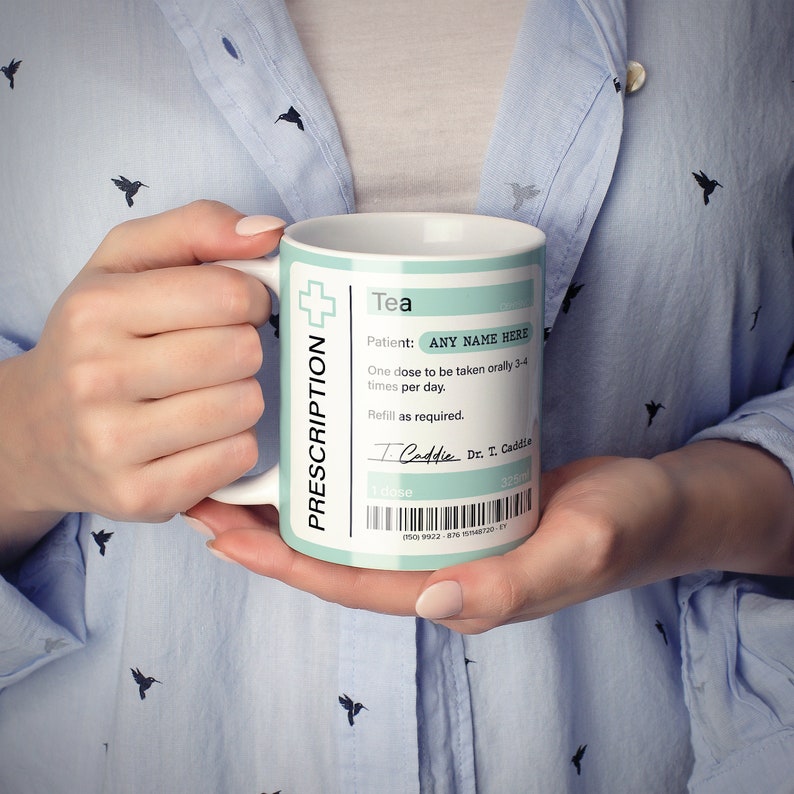 May include: White ceramic mug with a blue and green prescription label that reads "Tea" and "Patient: ANY NAME HERE". The label also includes instructions for taking the tea, a signature, and a barcode.