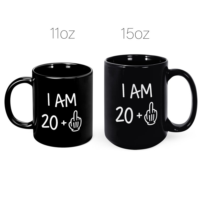May include: Two black coffee mugs with white text that reads "I AM 20 +" with a middle finger emoji. The mug on the left is 11 oz and the mug on the right is 15 oz.