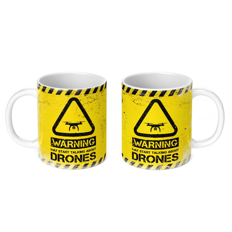 May include: Two white ceramic mugs with a yellow and black warning sign design. The sign features a drone icon and the text "WARNING MAY START TALKING ABOUT DRONES".
