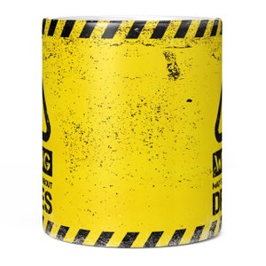 May include: Yellow coffee mug with a black warning sign that says "Warning May Cause Dreams". The sign has a black and yellow striped border.