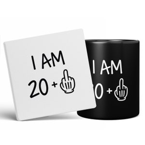 May include: A white ceramic coaster and a black ceramic mug with the text "I AM 20+" and "I AM 30+" with a middle finger emoji on each.