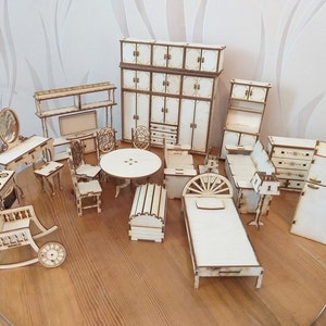 Op de afbeelding: Een verzameling miniatuur houten poppenhuismeubels, waaronder een bed, schommelstoel, tafel, stoelen, kasten en een dressoir. De meubels zijn onafgewerkt en klaar om te worden geverfd of gebeitst. De stukken zijn gerangschikt op een houten oppervlak.