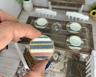 May include: Set of four blue and white striped fabric placemats with a burlap trim. The placemats are round and have a pink stripe in the center.