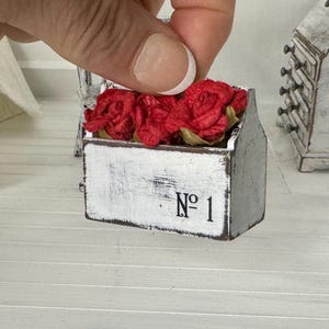 May include: A white wooden box with red fabric flowers inside. The box has a distressed white paint finish and the number "No. 1" written on the front.