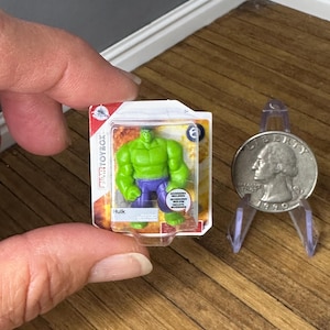 May include: A miniature Hulk action figure in a clear plastic package with a red and white border. The Hulk figure is green with purple pants. A 1990 quarter is displayed next to the figure.