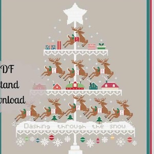 Puede incluir: Arte de punto de cruz enmarcado con un diseño de árbol de Navidad. El árbol está adornado con renos, regalos y casas, con el texto "Dashing through the snow". La obra de arte está enmarcada en un marco blanco.