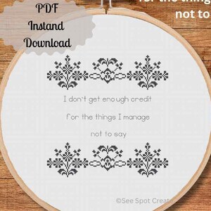 May include: A cross-stitch embroidery hoop with the text "I don't get enough credit for the things I manage not to say." The design includes black floral patterns above and below the text. The words "PDF Instant Download" are also visible.