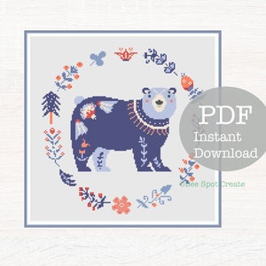 May include: A cross-stitch pattern featuring a stylized bear in shades of blue, with floral and geometric accents. The bear is surrounded by a wreath of flowers and leaves. The text "PDF Instant Download" is visible.