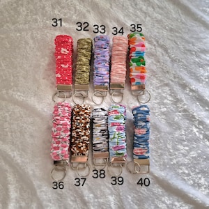 May include: Ten fabric-covered wristlet keychains arranged in two rows, numbered 31 through 40. Each keychain features a gathered, elasticized textile band in various patterns and colors, attached to a silver-toned metal clasp with a split ring.