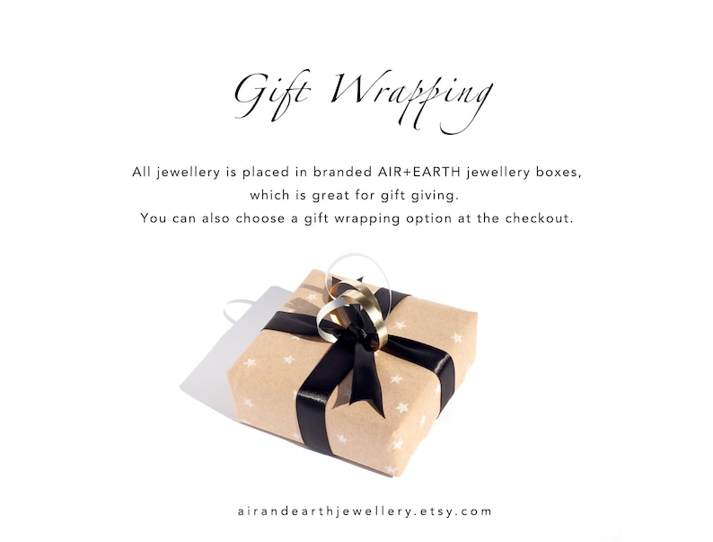 May include: A square gift box wrapped in light brown paper with a white star pattern, tied with a black satin ribbon and a gold metallic loop. The text reads: Gift Wrapping, All jewellery is placed in branded AIR+EARTH jewellery boxes, airandearthjewellery.etsy.com.